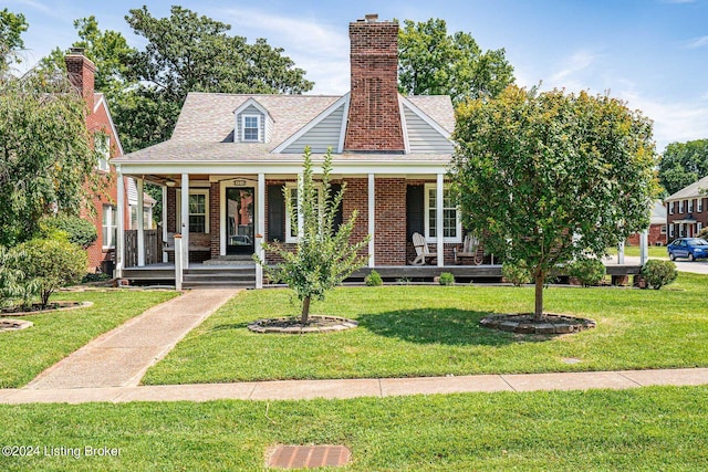 view of front of house with a front lawn, covered porch, and a chimney