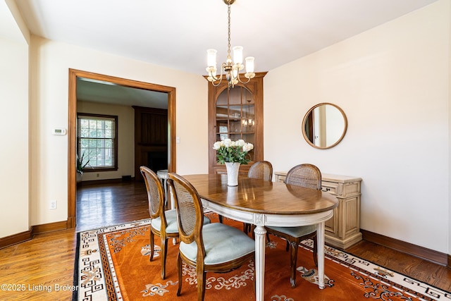 dining space with an inviting chandelier, light wood-style flooring, and baseboards