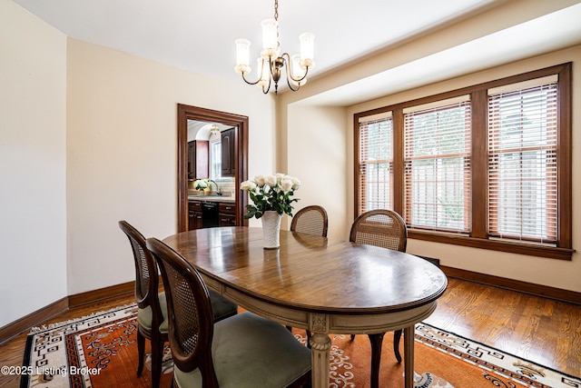 dining space featuring baseboards, a notable chandelier, and wood finished floors