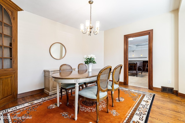 dining room featuring visible vents, baseboards, a notable chandelier, and light wood finished floors