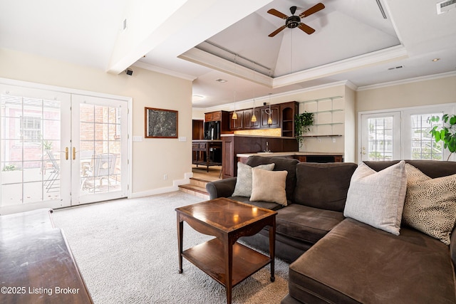 living room featuring a tray ceiling, visible vents, ceiling fan, and ornamental molding