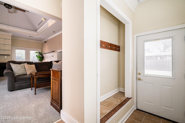 mudroom with a ceiling fan, a tray ceiling, carpet flooring, crown molding, and tile patterned flooring