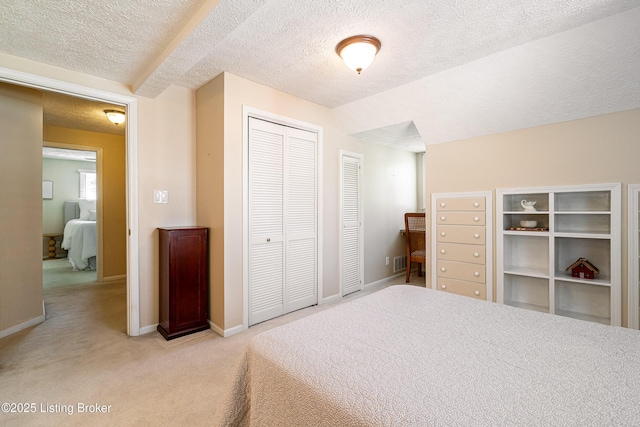 bedroom with visible vents, baseboards, a closet, a textured ceiling, and light colored carpet