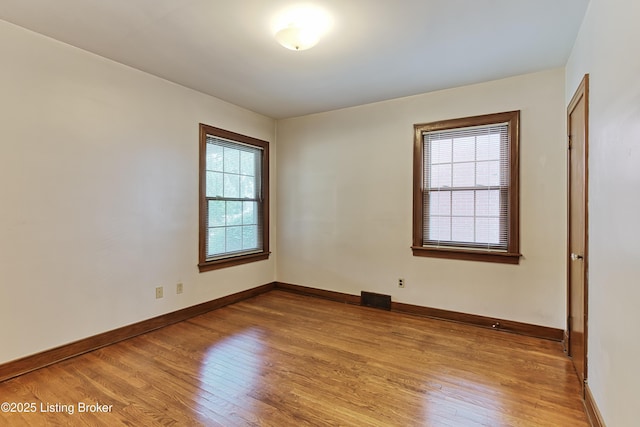 empty room featuring light wood-type flooring, visible vents, and baseboards