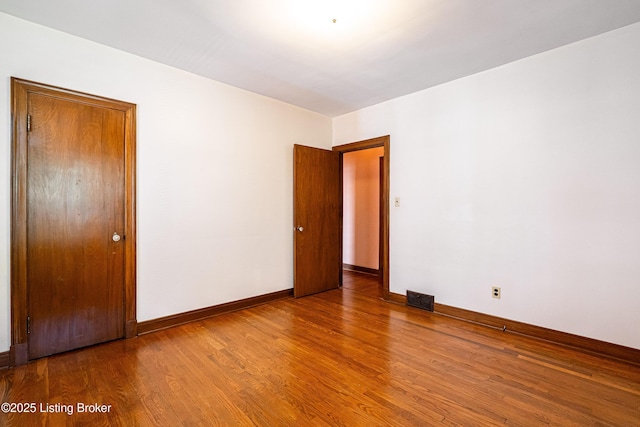 spare room with visible vents, baseboards, and wood finished floors