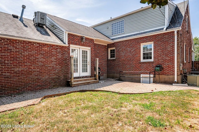 rear view of house with entry steps, central AC, a yard, brick siding, and a patio area