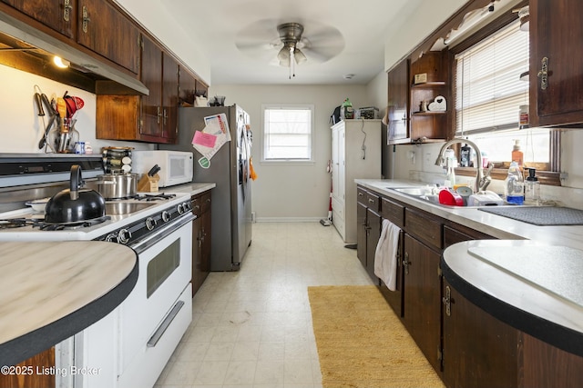 kitchen with a sink, under cabinet range hood, light countertops, white appliances, and open shelves