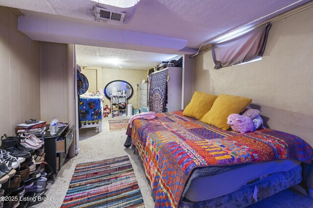 carpeted bedroom featuring visible vents, a textured ceiling, and a textured wall