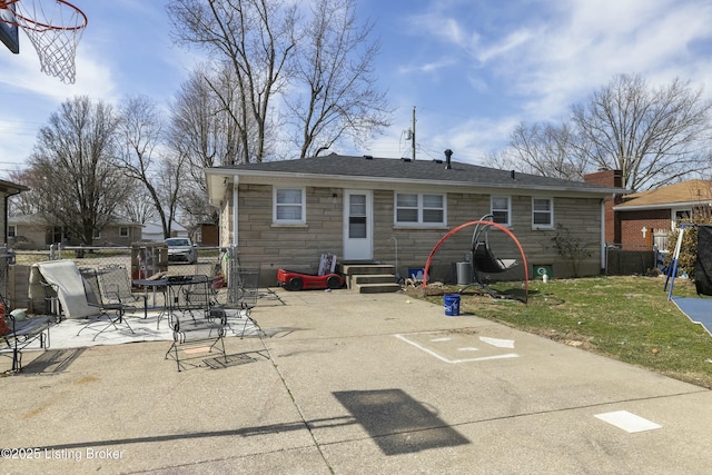 back of house with a lawn, entry steps, stone siding, fence, and a patio area