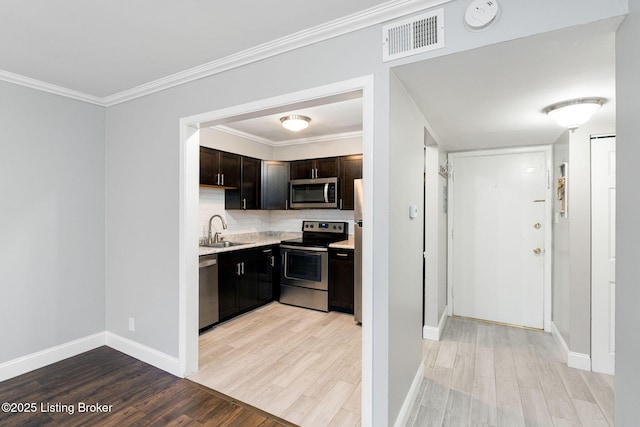 kitchen featuring visible vents, light wood-style flooring, a sink, appliances with stainless steel finishes, and light countertops