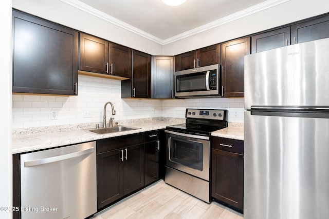 kitchen featuring dark brown cabinetry, ornamental molding, decorative backsplash, stainless steel appliances, and a sink