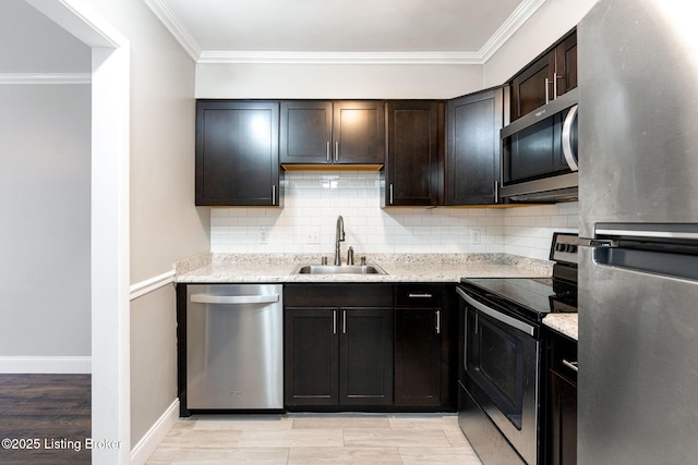 kitchen featuring light wood finished floors, a sink, stainless steel appliances, crown molding, and tasteful backsplash