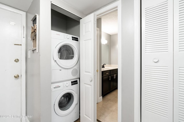 washroom featuring laundry area, a sink, and stacked washer and dryer