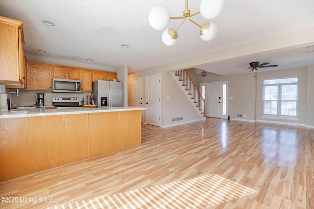 kitchen with light countertops, a peninsula, visible vents, and stainless steel appliances