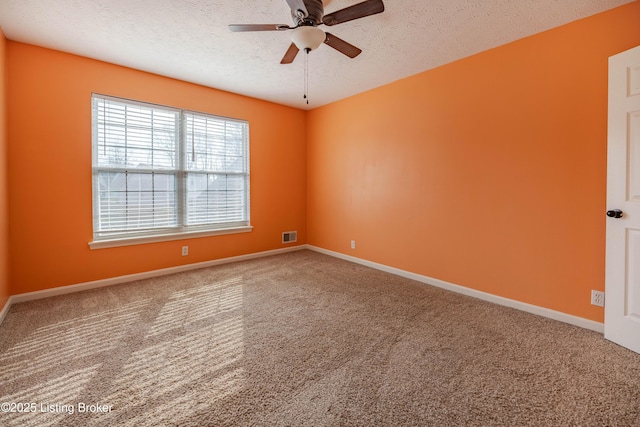 carpeted spare room with visible vents, baseboards, a textured ceiling, and a ceiling fan