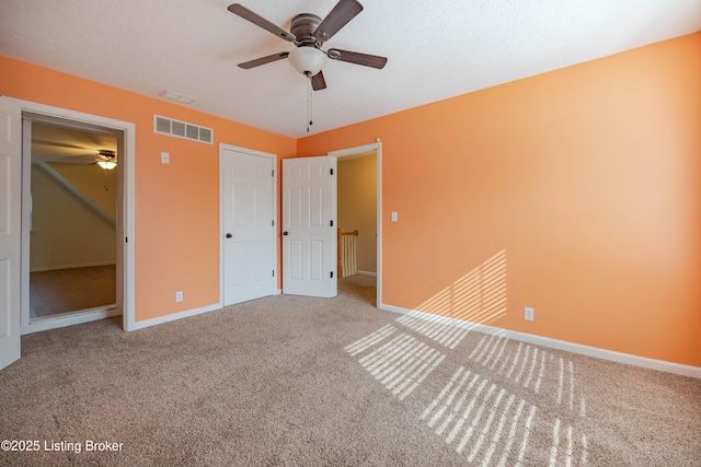 unfurnished bedroom featuring visible vents, ceiling fan, carpet, and baseboards