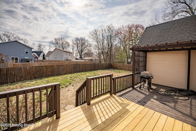 wooden deck with a lawn, a grill, and a fenced backyard