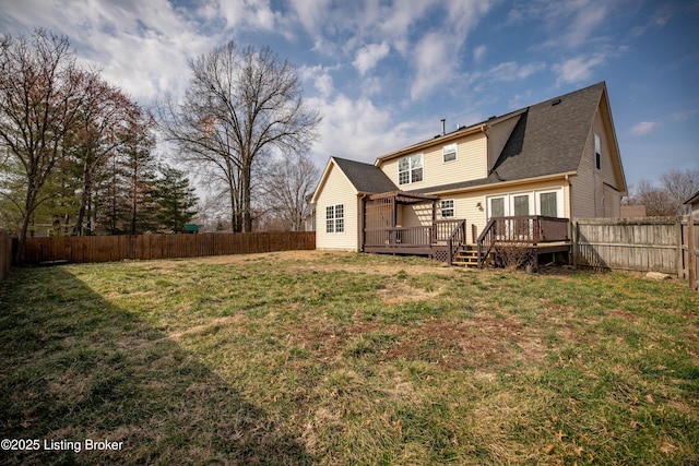 back of property with a yard, a wooden deck, a fenced backyard, and roof with shingles