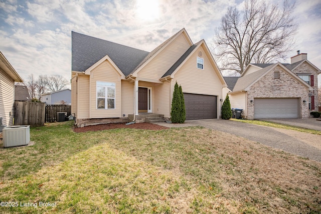 view of front facade with a front lawn, driveway, fence, cooling unit, and a garage