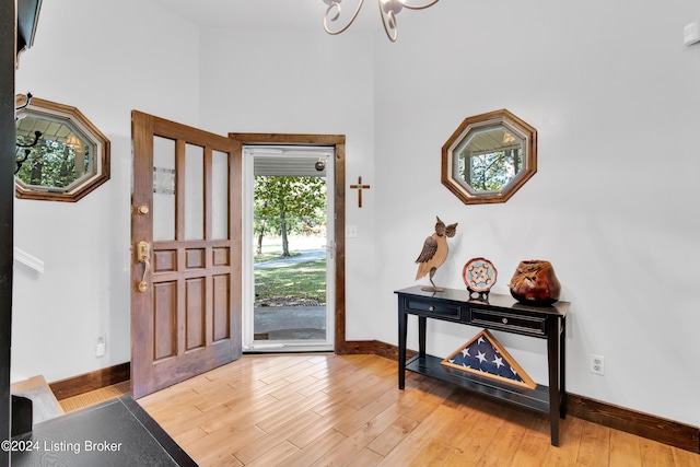 foyer featuring light wood-type flooring, baseboards, and a notable chandelier