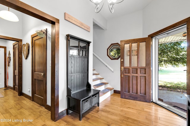 foyer with stairs, light wood-style floors, baseboards, and a chandelier