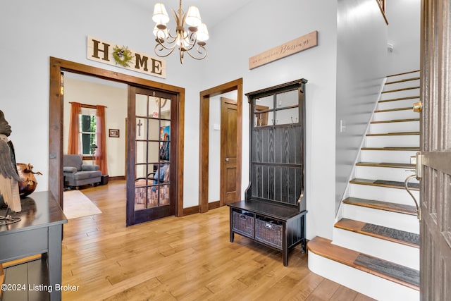 interior space featuring stairway, light wood-style flooring, baseboards, and an inviting chandelier