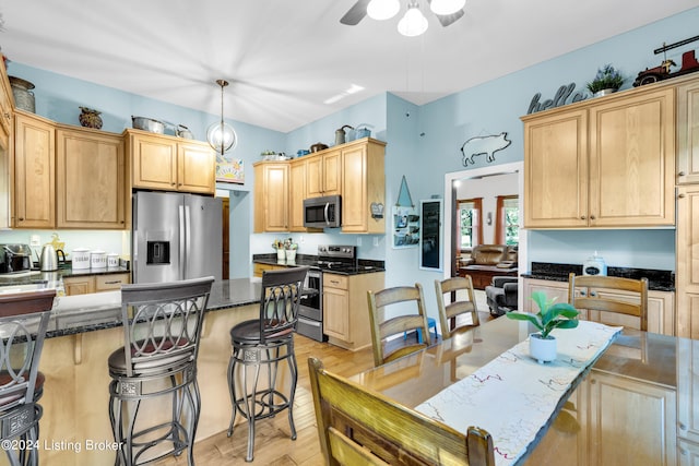 kitchen with light brown cabinets, stainless steel appliances, and a kitchen breakfast bar