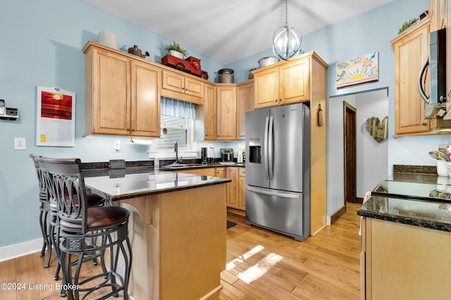 kitchen with a sink, a kitchen breakfast bar, stainless steel fridge, a peninsula, and light wood finished floors