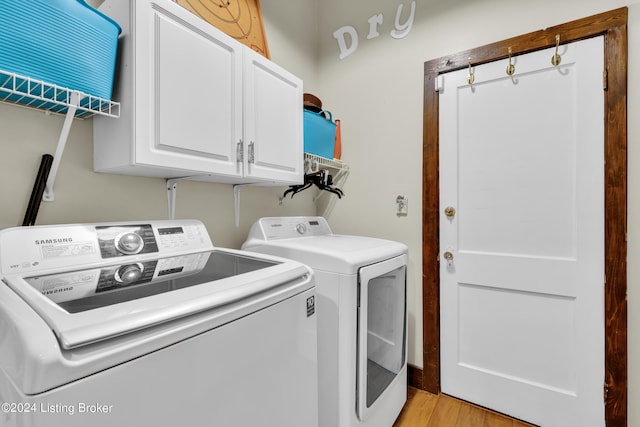 laundry room featuring cabinet space, light wood-style floors, and separate washer and dryer