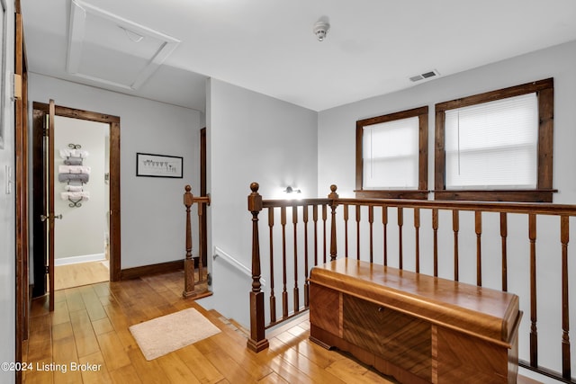 stairway featuring hardwood / wood-style flooring, attic access, baseboards, and visible vents