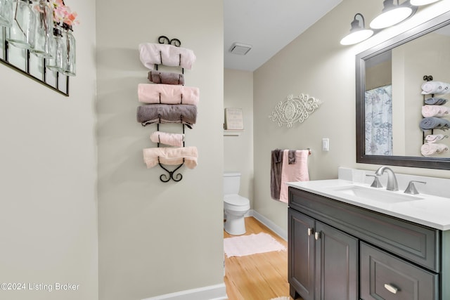 full bath featuring baseboards, toilet, wood finished floors, and vanity