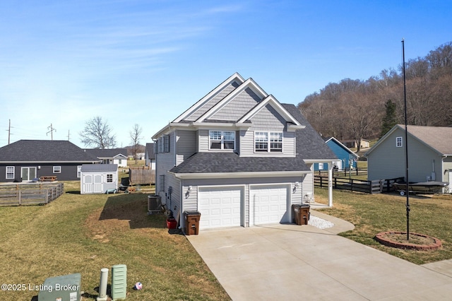 view of front of house featuring fence, a shed, driveway, a front lawn, and a garage