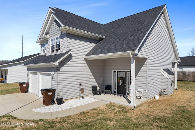 back of house with a yard, a garage, roof with shingles, and concrete driveway