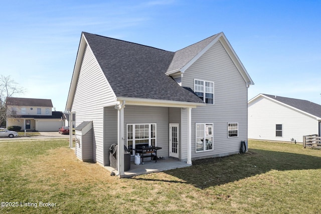 back of house with a lawn, a shingled roof, and a patio area