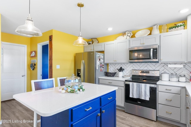 kitchen with a kitchen island, stainless steel appliances, decorative backsplash, light countertops, and light wood-type flooring