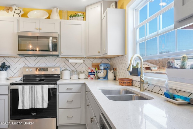 kitchen with light stone countertops, tasteful backsplash, appliances with stainless steel finishes, and a sink