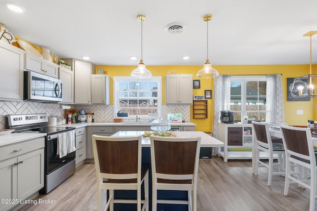 kitchen with light countertops, light wood finished floors, appliances with stainless steel finishes, and a sink