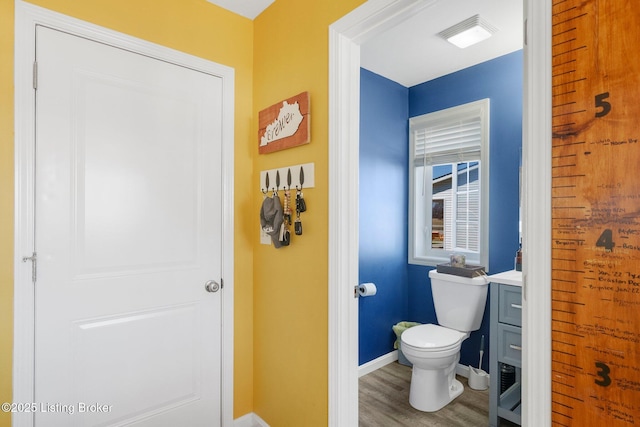 bathroom featuring visible vents, toilet, wood finished floors, baseboards, and vanity