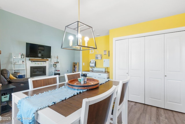 dining space featuring a chandelier, a glass covered fireplace, and wood finished floors