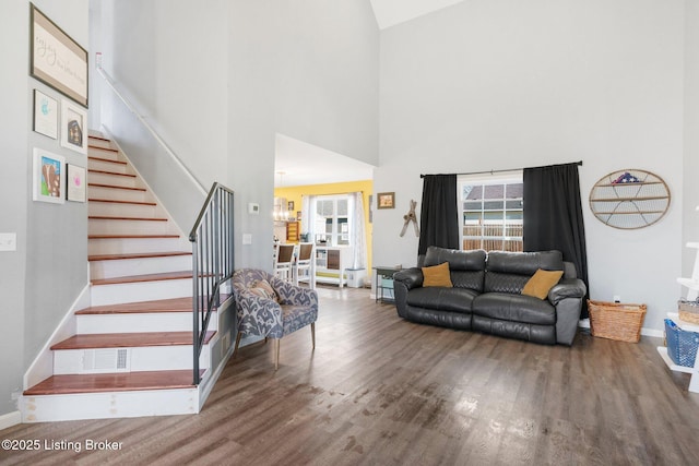 living area featuring visible vents, baseboards, wood finished floors, and stairs