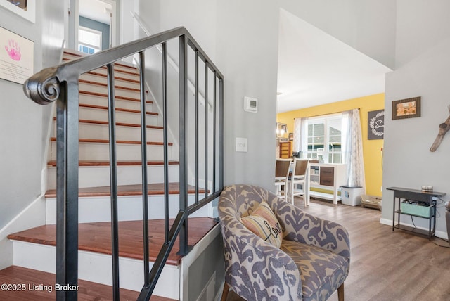 staircase with a high ceiling, wood finished floors, and baseboards