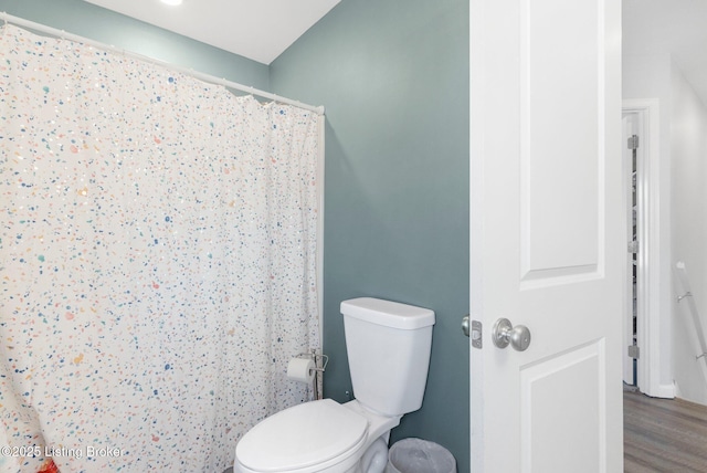 bathroom with curtained shower, toilet, and wood finished floors