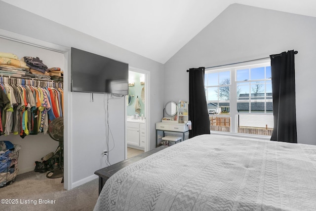 carpeted bedroom with a walk in closet, a sink, connected bathroom, a closet, and lofted ceiling