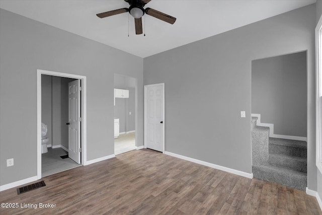 unfurnished bedroom featuring connected bathroom, wood finished floors, visible vents, and baseboards