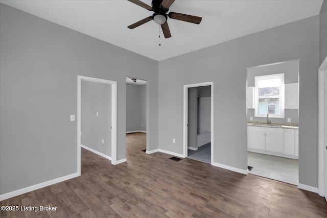 unfurnished living room featuring visible vents, baseboards, wood finished floors, a ceiling fan, and a sink