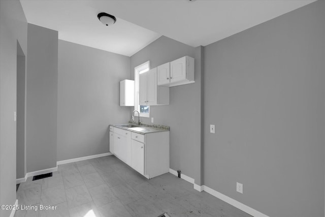 interior space featuring white cabinetry, light countertops, baseboards, and a sink