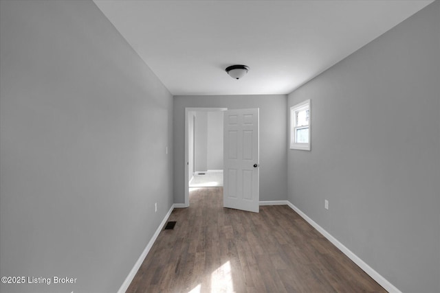 empty room with wood finished floors, baseboards, and visible vents