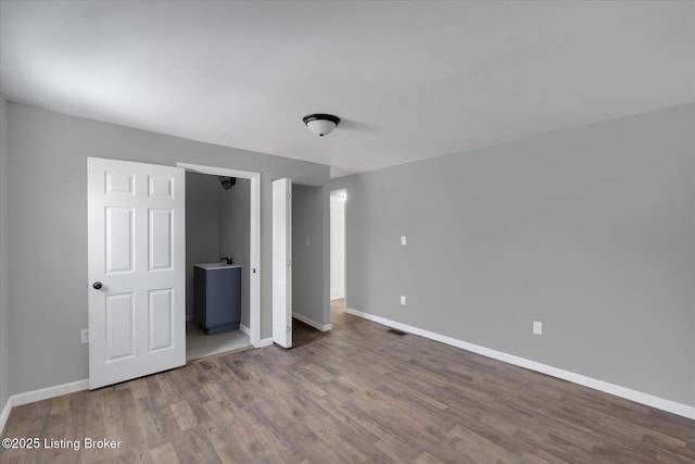 unfurnished bedroom with visible vents, wood finished floors, and baseboards