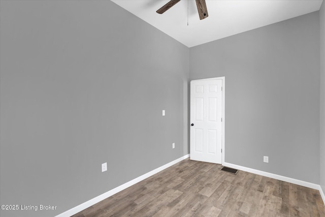 unfurnished room featuring wood finished floors, baseboards, visible vents, and ceiling fan