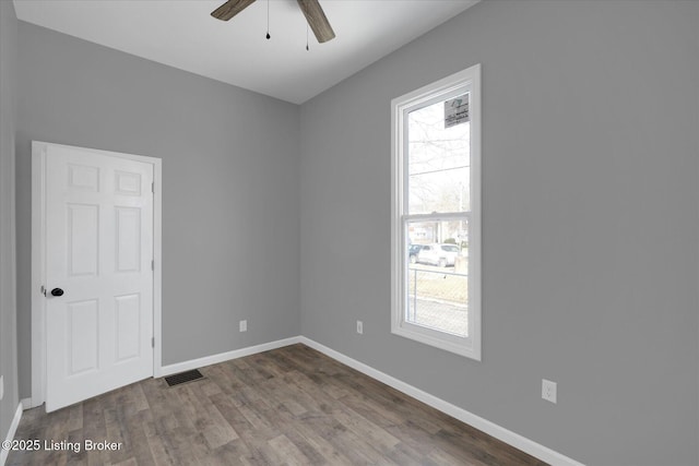 spare room featuring visible vents, baseboards, dark wood-type flooring, and a ceiling fan